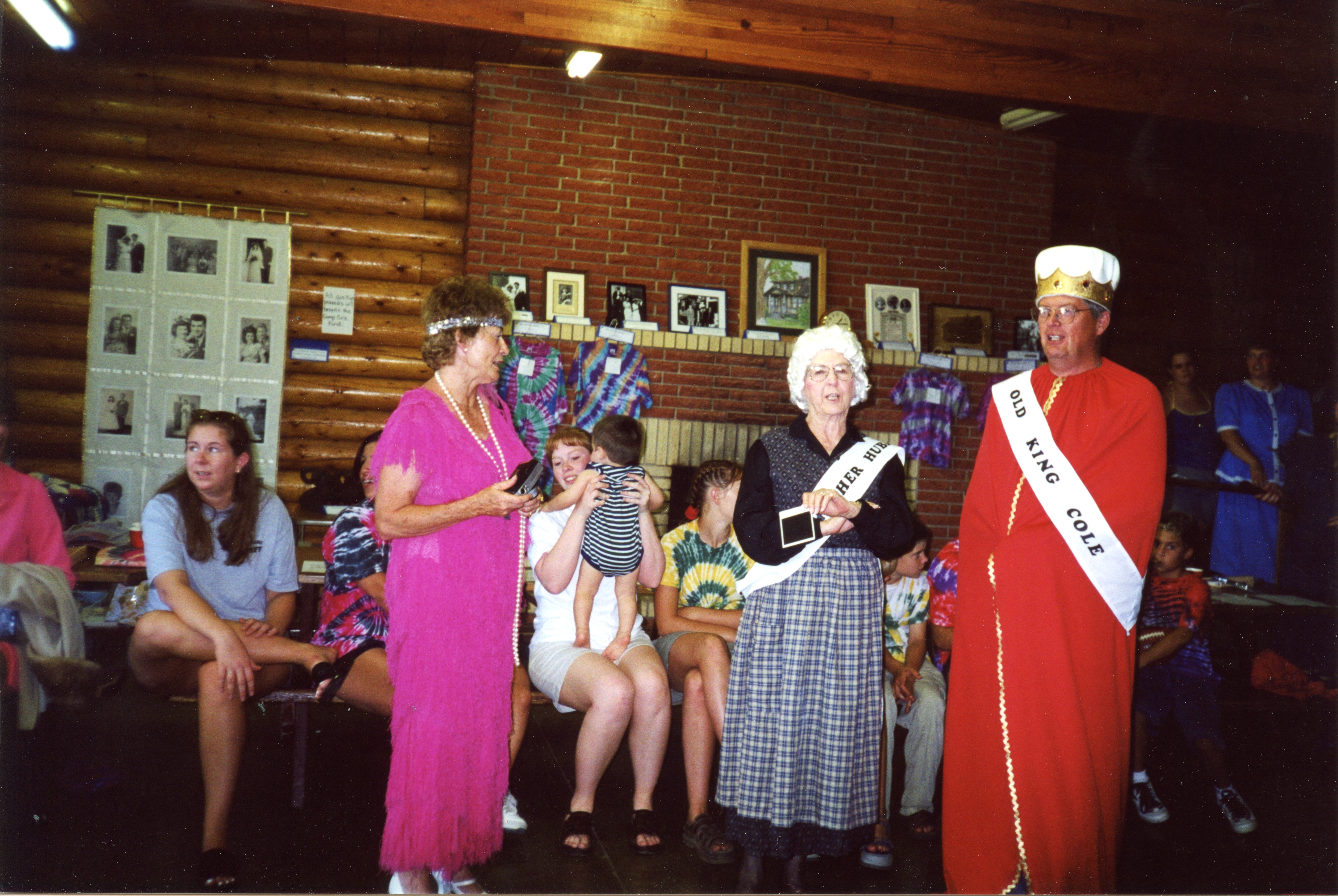 Anne LaCroix visits with Thelma and John McLain, costume contest winners, in front of the auction items during the 2000 reunion in the Bear Paw Mountains near Havre, Montana.